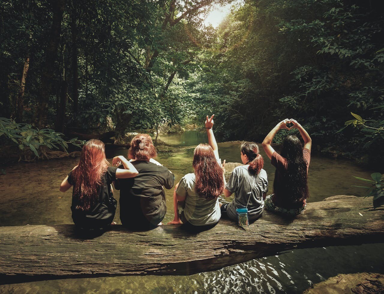 women sitting on a log over a river